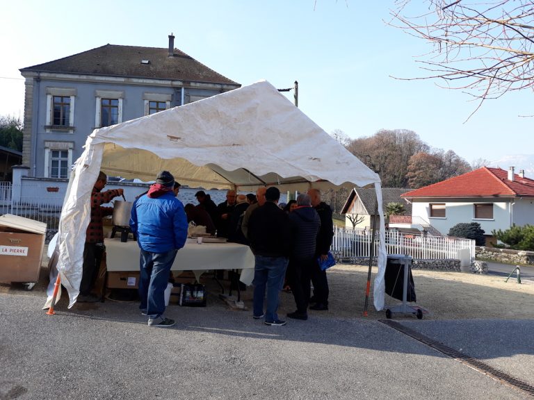Habitants réunis sous une tente devant la mairie lors d'un événement villageois