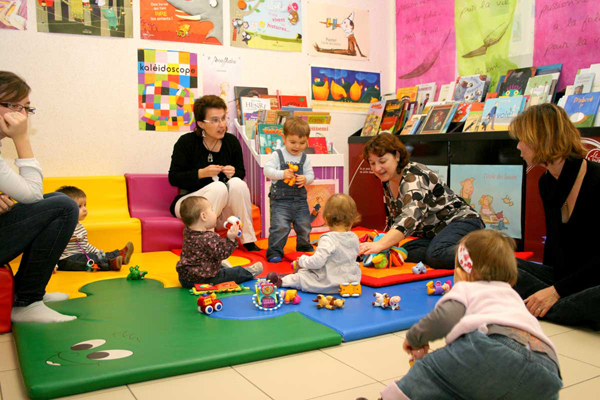 Enfants et assistantes maternelles réunis autour de livres et de jeux