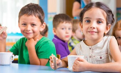 Enfants souriants prenant leur goûter à la cantine