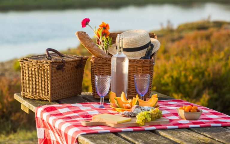 Panier pique-nique dressé avec pain, fromage et fruits, au bord de l'eau