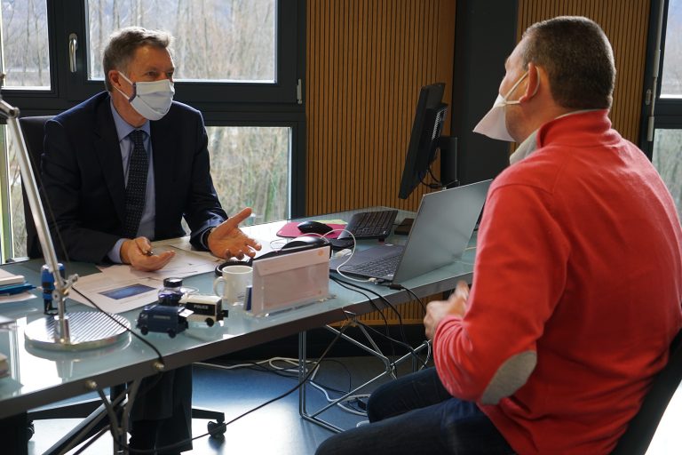 Entretien entre deux hommes portant un masque sanitaire dans un bureau