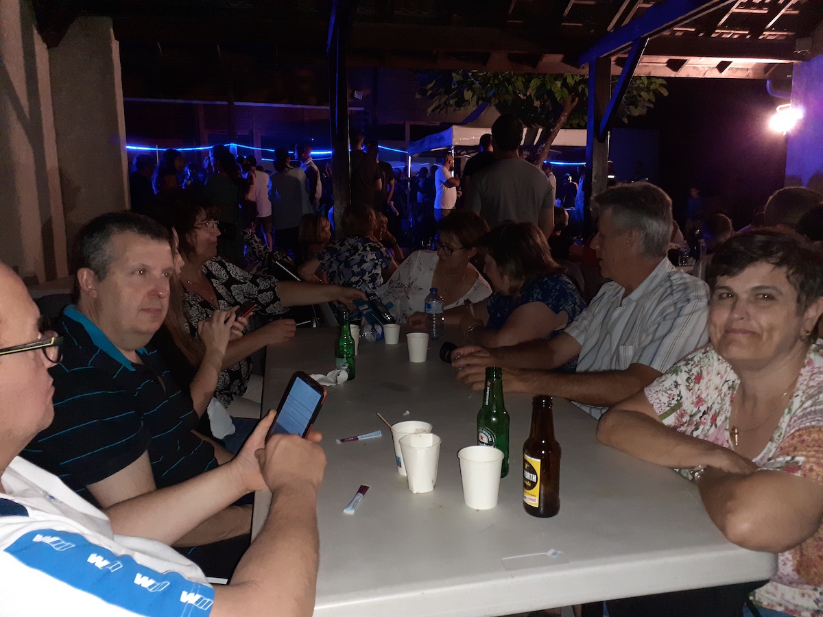 Convives réunis en soirée sous une salle éclairée de bleu lors d'une fête villageoise