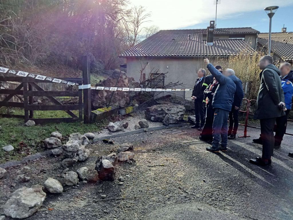 Inspection d'un éboulement de rochers près d'une habitation, route sécurisée par un ruban de balisage