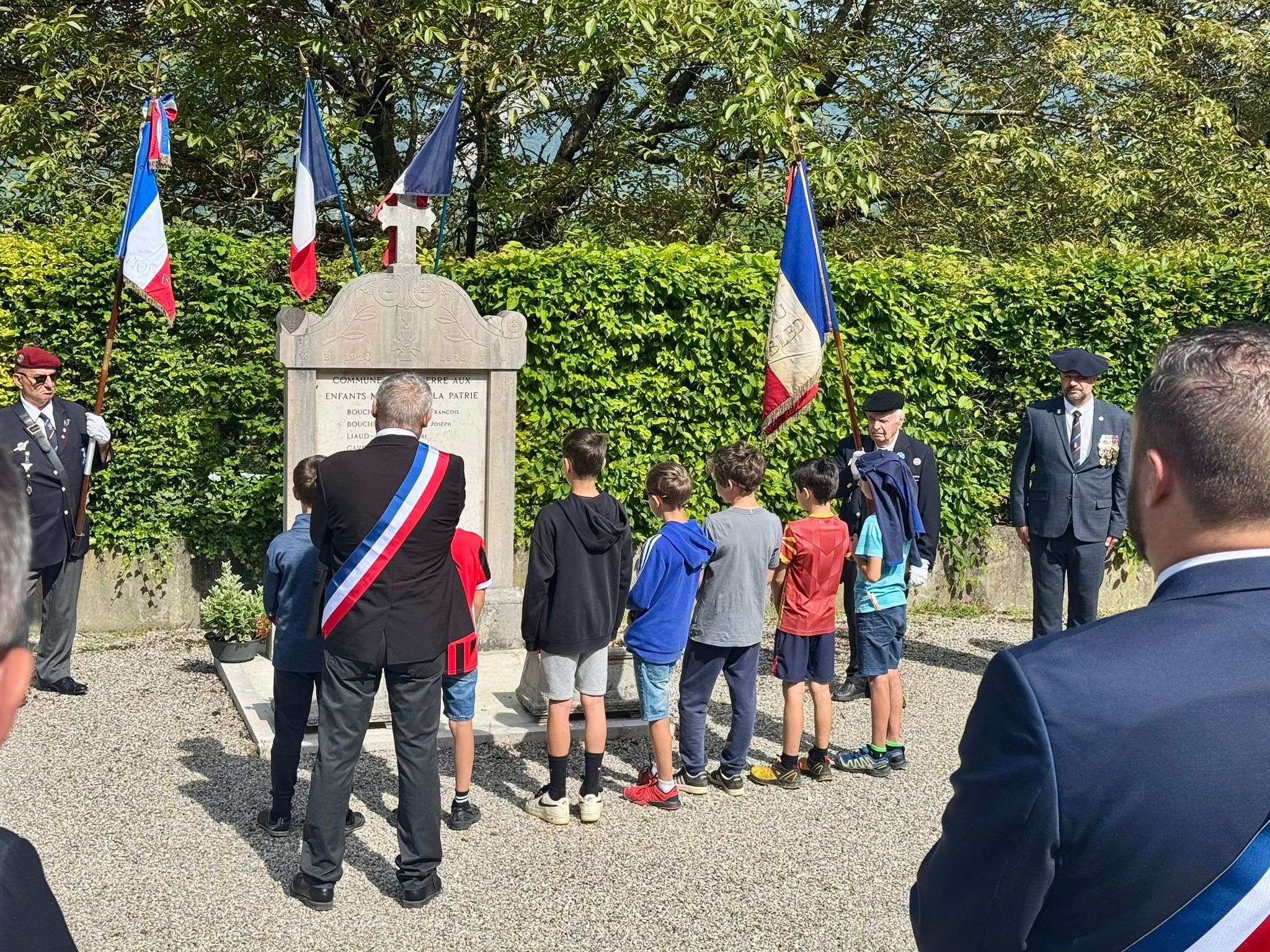 Cérémonie commémorative au monument aux morts, avec des élus et des enfants du village