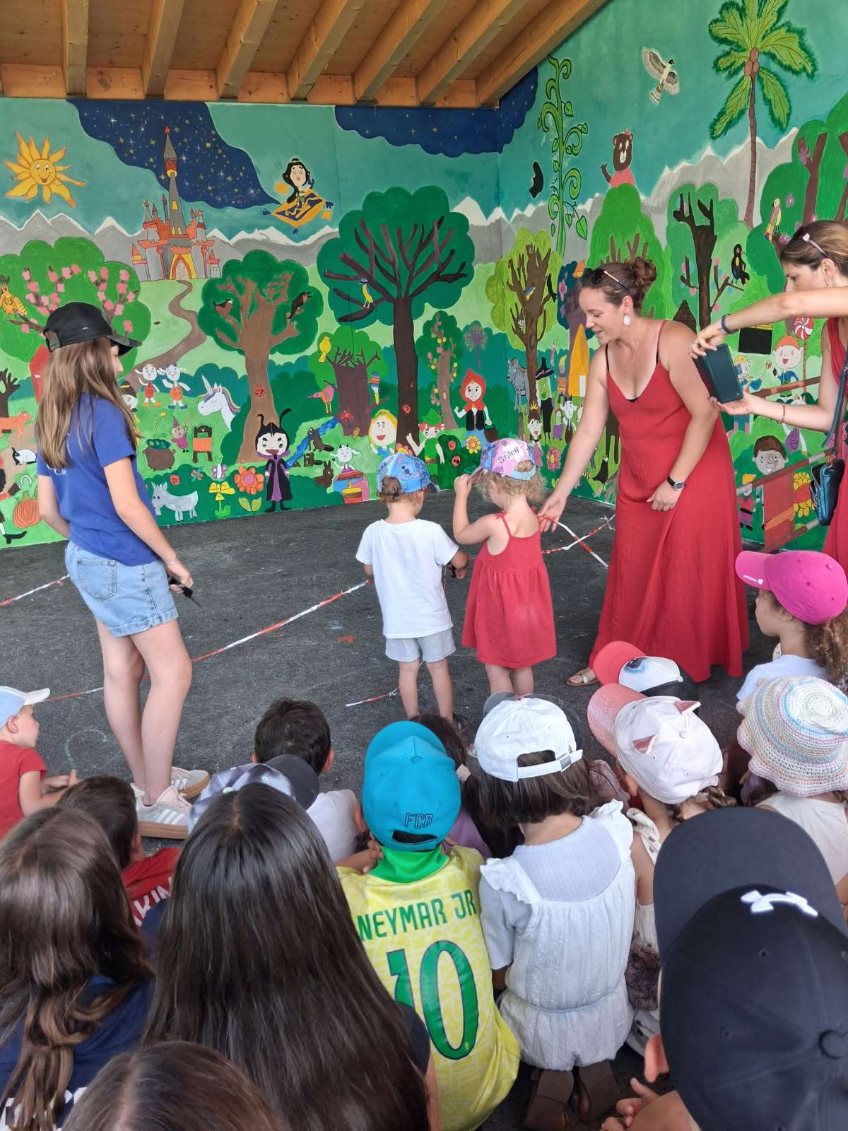 Enfants réunis devant une fresque murale illustrée, lors d'une animation scolaire